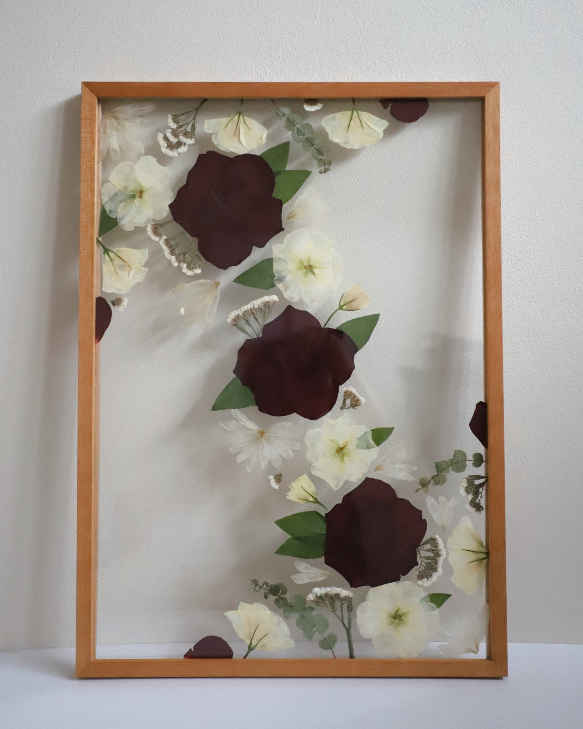 Custom framed artwork with pressed flowers on a white background